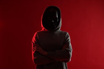 Anonymity. Woman wearing mask on red background