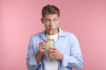Man drinking lemonade from mason jar on pink background. Refreshing drink