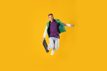 Man with skateboard jumping on orange background