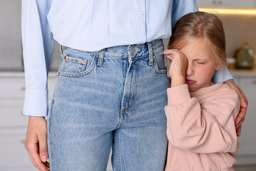 Little girl afraid to leave without mother and clinging to her at home. Separation anxiety