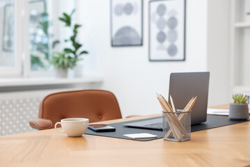 Stylish workplace with modern laptop and stationery on wooden desk indoors