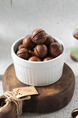 Nutty brown balls sit in a white bowl on a wooden board surrounded by greenery in a cozy kitchen setting