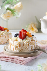 Delicious pavlova dessert topped with fresh strawberries, blueberries, and apricots in a cozy kitchen setting