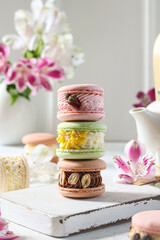 Delicate macarons stacked elegantly in a cozy kitchen with floral accents during a bright afternoon gathering