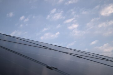 Angled photovoltaic solar panels under clear blue sky with scattered clouds and wide copy space for...