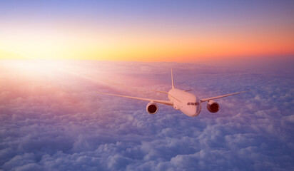 White passenger airplane flying in the sky amazing clouds in the background at sunset - Travel by...