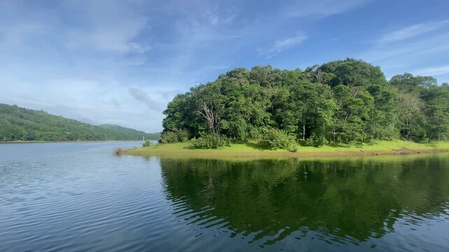 Scenic view of Periyar Lake in Thekkady, Kerala, India &mdash; tranquil waters reflecting lush green forest under a clear blue sky.