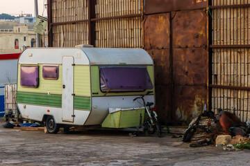 Old Caravan by Industrial Yard Gate with Bicycle and Ropes