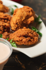 Close-up view of fried chicken with vegetables and sauce.