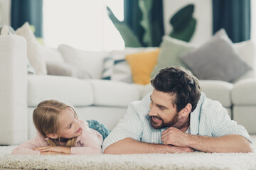 Cheerful father and daughter bonding in a cozy living room sharing smiles and creating special...