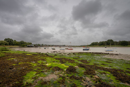 River Deben at low tide with small boats under a stormy sky. View towards the historic town of Woodbridge in Suffolk, UK. - Powered by Adobe