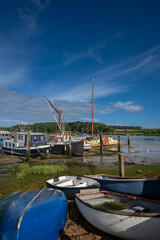 Small boats on a sunny day. View of the quay at low tide on the River Deben in the historic town of Woodbridge in Suffolk, UK.