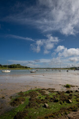 River Deben at low tide with small boats on a sunny day. View near the historic town of Woodbridge in Suffolk, UK.