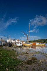 Boats on a sunny day at the quay in the historic town of Woodbridge in Suffolk, UK. View at low tide on the River Deben.