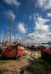 Boats sitting on mud under a stormy sky. View of the quay at low tide on the River Deben in the historic town of Woodbridge, Suffolk, UK.