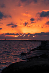 Obraz premium Dramatic fiery orange sunset over the Baltic Sea with a lighthouse silhouette in Riga, Latvia.