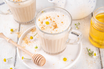 Calming natural chamomile flowers tea latte, organic late night cozy warm beverage with milk and floral chamomile tea, with honey and ginger spices