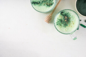 Healthy spirulina latte drink. Caffeine-free green spirulina infused, calming beverage, with spirulina powder, pills and capsules on white table background