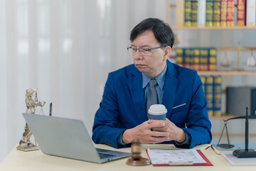 Obraz premium A lawyer or accountant working with a laptop at his desk, reviewing case files in a sharp suit, is sitting at his desk.