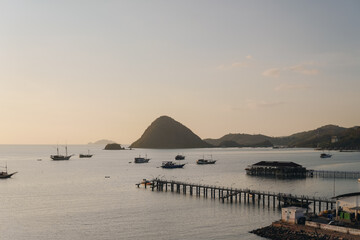 Beautiful scenery of tropical island harbor with long bridge pier and boats in Labuan Bajo.