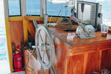 Wheelhouse control board with wooden steering wheel inside a boat.