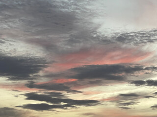 A stunning sky at sunset, showcasing dramatic clouds with hues of pink and blue, creating a serene...