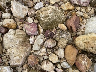 A close-up view of various rocks and pebbles in different shapes, sizes, and colors, creating a...
