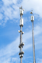 Fototapeta premium Cell tower against a blue sky with clouds. Mobile communication, antenna, 5g, 4g technology concept. Data transfer.