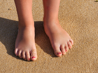 small children's feet with red colored nails in the sand on the beach, vacation with children,...