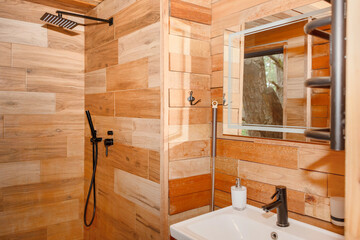 A cozy wooden shower interior showcasing natural wood paneling and a window overlooking outdoor...