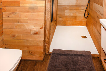A cozy wooden shower interior showcasing natural wood paneling and a window overlooking outdoor...