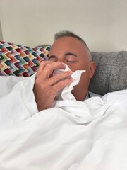 Young adult man sick on the couch at home. Adult boy lying on the couch with flu and fever. Man on...