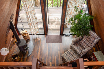 Charming wooden attic interior with a ladder accessing a loft, armchair, and rustic decor. Snug living area, wooden aesthetics and a warm atmosphere. Countryside living, relaxation, and cozy homes.