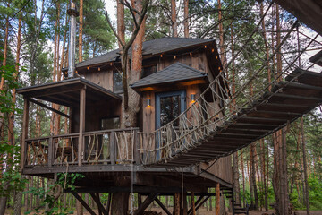 A charming wooden treehouse among tall trees in a forest setting. Concepts of eco-living,...