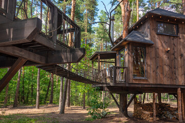 A charming wooden treehouse among tall trees in a forest setting. Concepts of eco-living,...