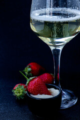 Refreshing sparkling drink accompanied by fresh strawberries and creamy dessert presented on a dark background