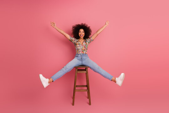 Charming young woman in stylish casual wear poses playfully with bright smile against vibrant pink backdrop