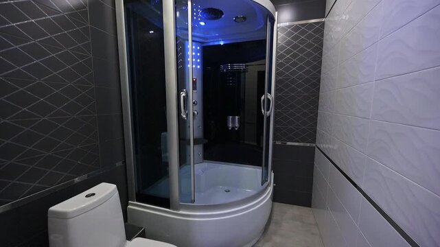 bathroom features a modern shower cabin with blue ambient lighting, contrasted by tiled walls