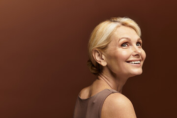 Joyful senior woman embracing beauty with a radiant smile against a warm backdrop