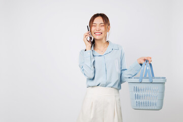 Excited Grocery shopping Asian woman talking speak on mobile phone, holding basket and smiling,...