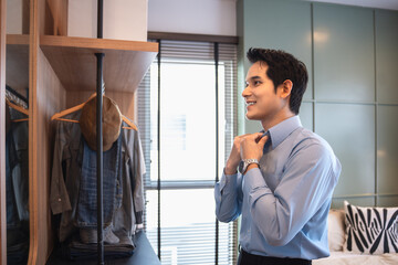Young asian man dressed in front of the mirror ready for office