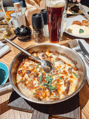 Delicious portion of beef stroganoff, served in a hot skillet alongside a tall glass of dark beer...