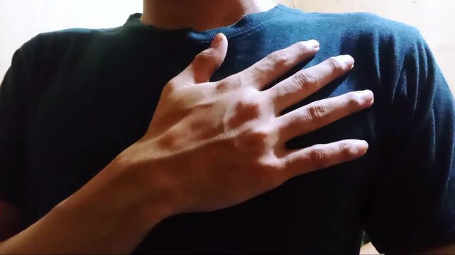 Closeup of a hand placed on the chest over a blue shirt, representing respect, oath, or emotional sincerity, ideal for cultural, symbolic, or emotional concepts in editorial and commercial use.