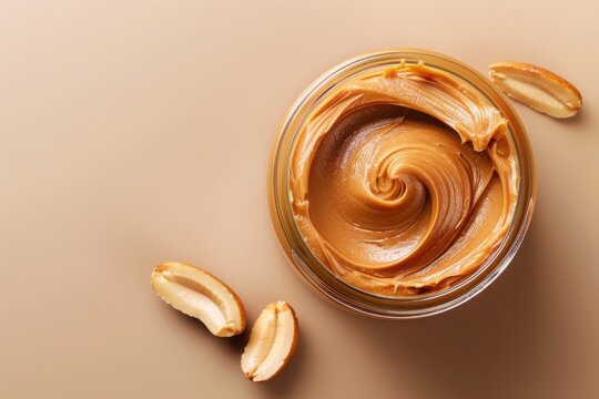 A jar of peanut butter with peanuts on a plain background