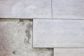 Partially laid gray ceramic tiles with leveling crosses show progress on a renovation project