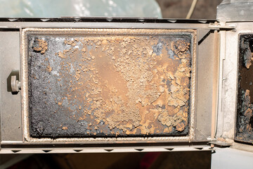 The inside of the solid fuel heater's stove door is heavily soiled and worn