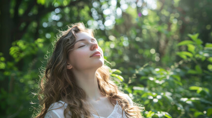 Young woman with long curly hair stands peacefully in a sunlit forest, surrounded by lush greenery, enjoying the tranquility of nature and embracing the moment of serenity