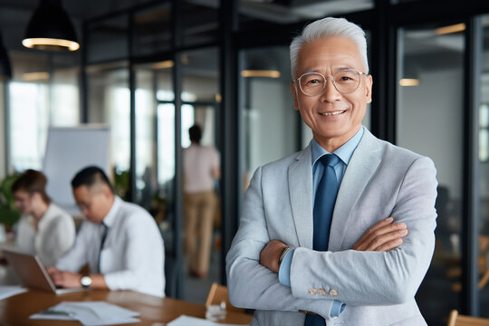 Smiling senior businessman with arms crossed in modern office setting