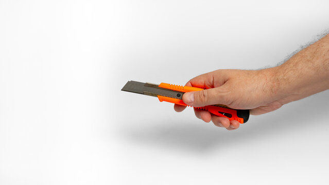 Red utility knife in hand isolated on white background. 