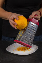 Chef rubs orange peel close-up in the kitchen